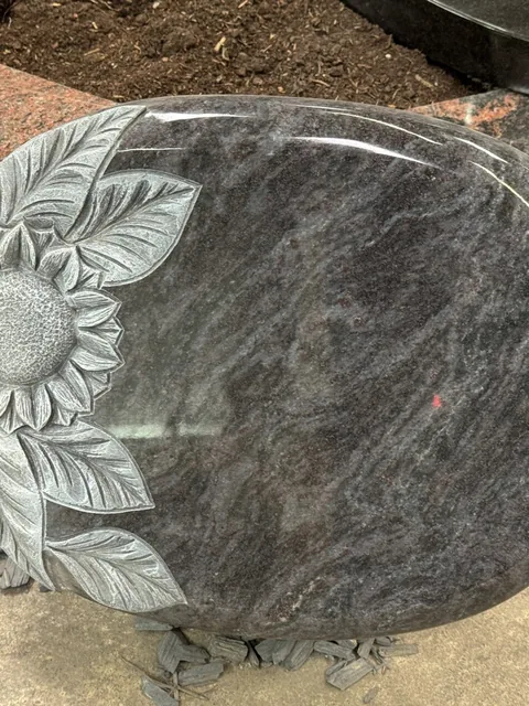 Liegende Grabplatte aus Naturstein mit gemeißelter Sonnenblume